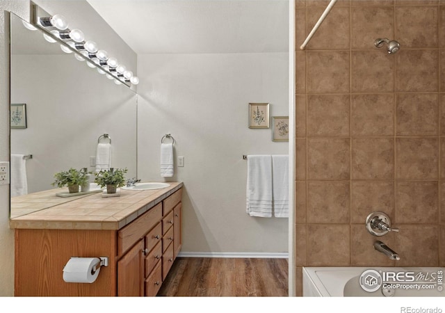 full bath featuring baseboards, vanity, wood finished floors, and shower / bathing tub combination