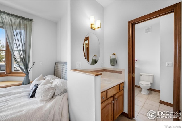 bedroom with baseboards, connected bathroom, and light tile patterned flooring