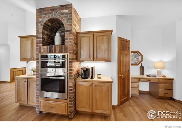 kitchen featuring light wood-style floors, light countertops, baseboards, and stainless steel double oven