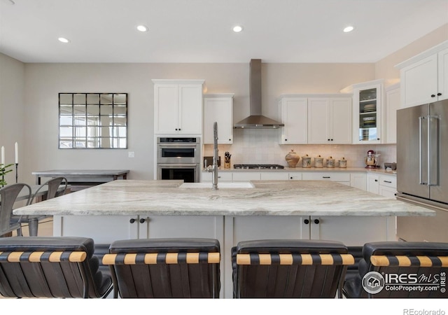 3351 Heron Lakes Pkwy, Berthoud, CO 80513 - kitchen featuring tasteful backsplash, a breakfast bar area, stainless steel appliances, wall chimney exhaust hood, and white cabinetry