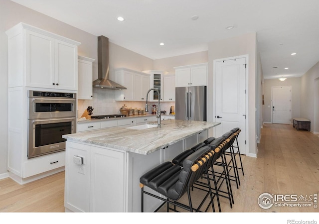 3351 Heron Lakes Pkwy, Berthoud, CO 80513 - kitchen featuring white cabinets, wall chimney exhaust hood, appliances with stainless steel finishes, and a sink