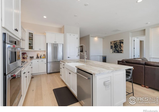 3351 Heron Lakes Pkwy, Berthoud, CO 80513 - kitchen featuring light wood finished floors, appliances with stainless steel finishes, white cabinetry, and a sink