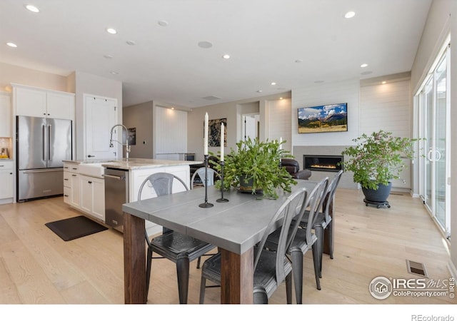 3351 Heron Lakes Pkwy, Berthoud, CO 80513 - dining space featuring recessed lighting, a glass covered fireplace, light wood-type flooring, and visible vents