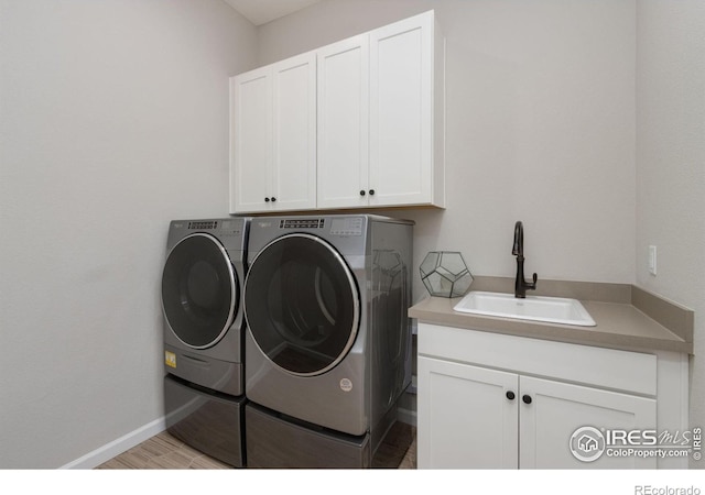 3351 Heron Lakes Pkwy, Berthoud, CO 80513 - washroom with washing machine and dryer, baseboards, cabinet space, and a sink