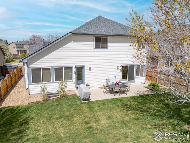 rear view of property featuring a lawn, a fenced backyard, a shingled roof, and a patio