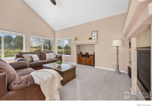 living room featuring a ceiling fan, light colored carpet, a fireplace, high vaulted ceiling, and baseboards