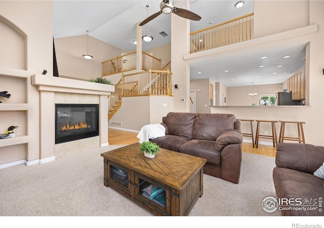 living area with stairway, high vaulted ceiling, ceiling fan, and visible vents