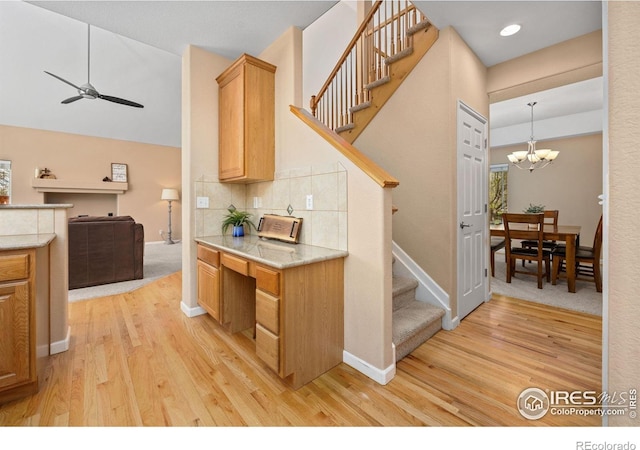 kitchen with light countertops, baseboards, ceiling fan with notable chandelier, and light wood-style flooring