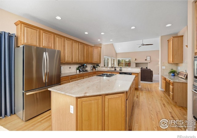 kitchen featuring a center island, backsplash, black appliances, and light wood-type flooring