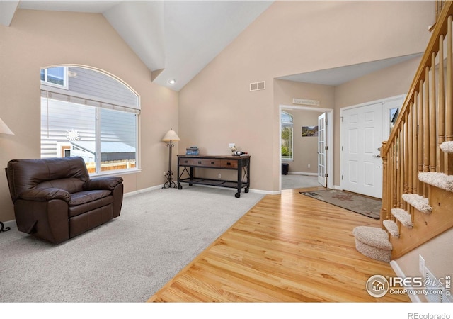 entryway with visible vents, stairs, wood finished floors, baseboards, and high vaulted ceiling