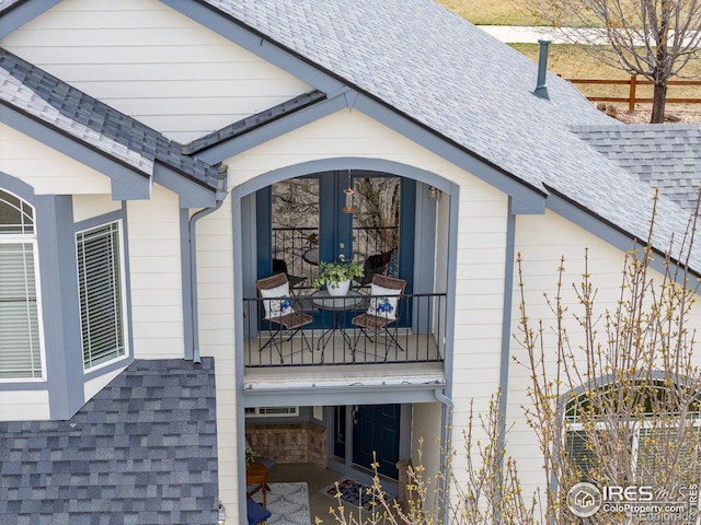 view of side of property featuring roof with shingles and a balcony