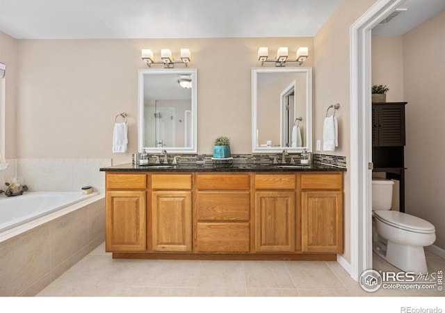 bathroom featuring a sink, tile patterned floors, double vanity, and a bath