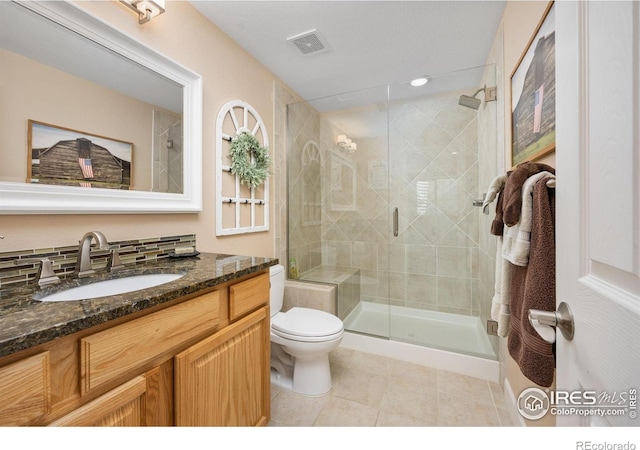 bathroom with tile patterned flooring, vanity, toilet, visible vents, and a stall shower