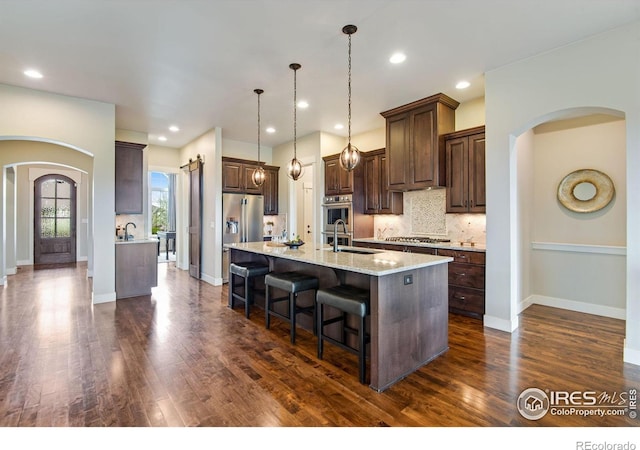 kitchen featuring arched walkways, dark wood-style flooring, and backsplash