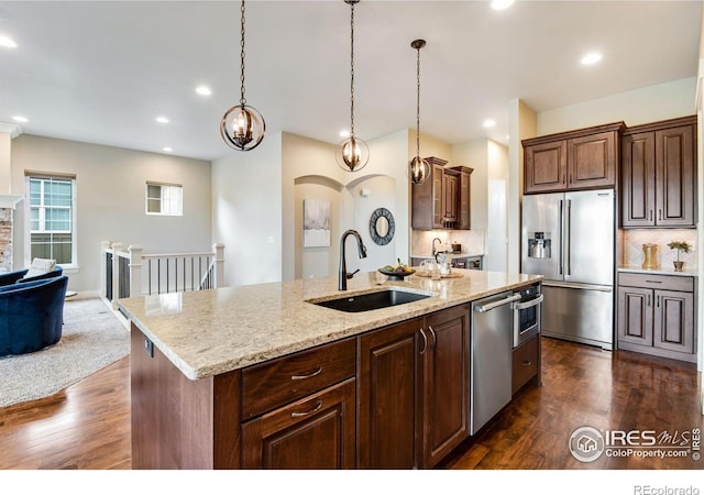 6297 Crooked Stick Dr, Windsor, CO 80550 - kitchen featuring stainless steel appliances, a sink, dark wood-type flooring, open floor plan, and a kitchen island with sink