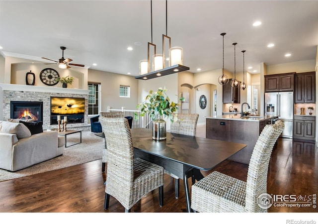 6297 Crooked Stick Dr, Windsor, CO 80550 - dining room with a ceiling fan, a glass covered fireplace, dark wood-type flooring, recessed lighting, and arched walkways