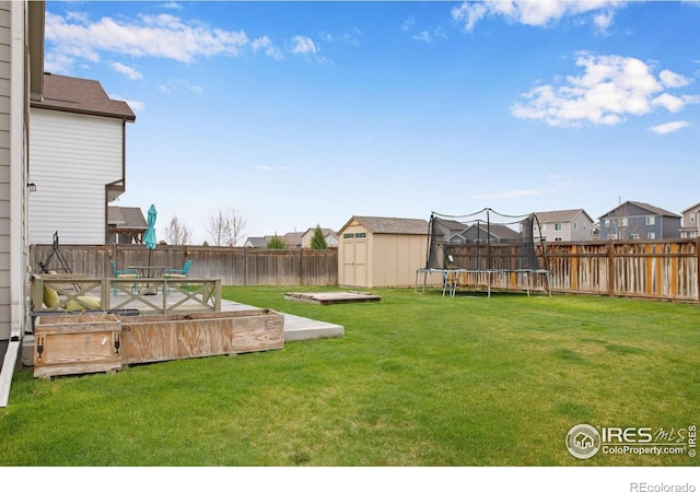 1484 Moraine Valley Dr, Severance, CO 80550 - view of yard featuring an outdoor structure, a wooden deck, a fenced backyard, a trampoline, and a storage shed