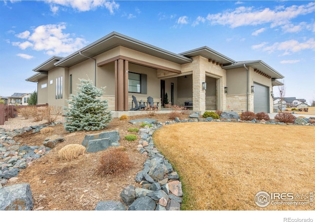 prairie-style home featuring an attached garage, stone siding, and stucco siding
