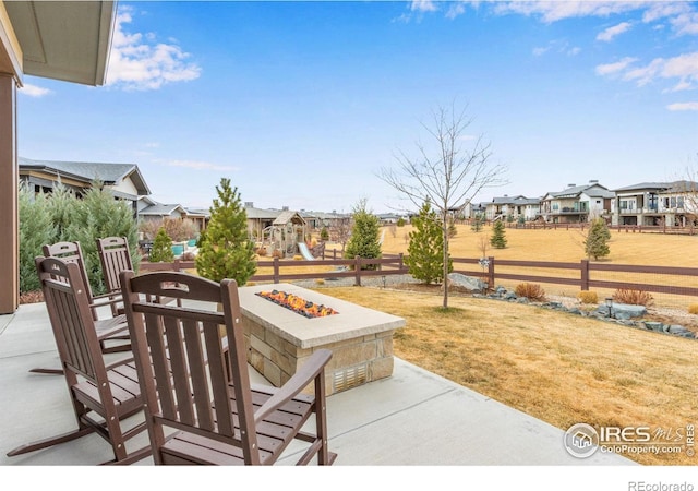 view of patio with a fire pit, fence, and a residential view