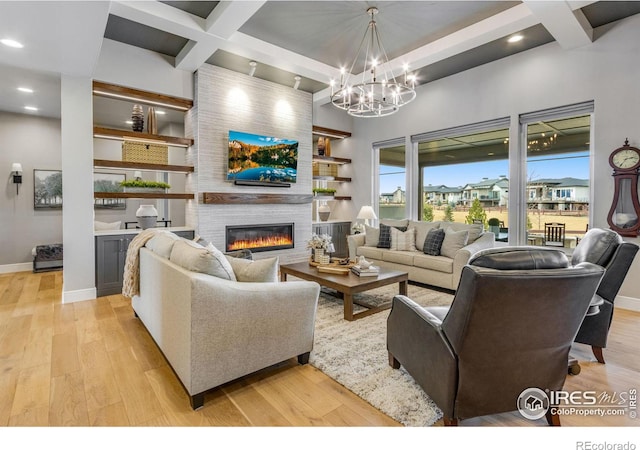 living room with light wood-style flooring, a large fireplace, and coffered ceiling