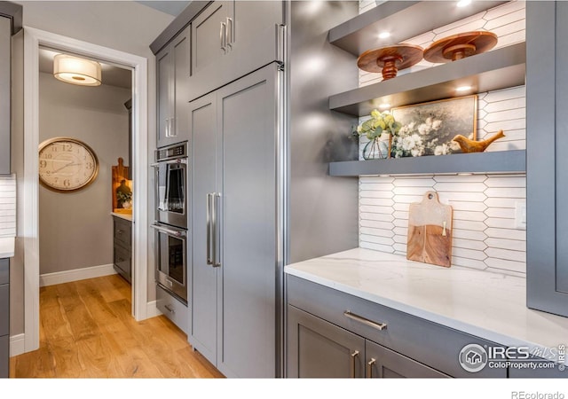 kitchen featuring open shelves, light wood-style floors, baseboards, and gray cabinets
