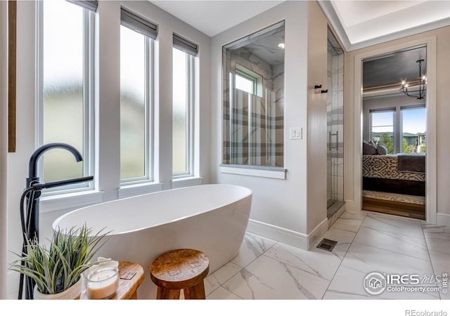 full bath with a shower stall, marble finish floor, a freestanding bath, ensuite bath, and baseboards