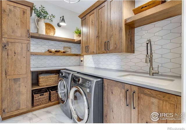 laundry area with cabinet space, washing machine and clothes dryer, marble finish floor, and a sink