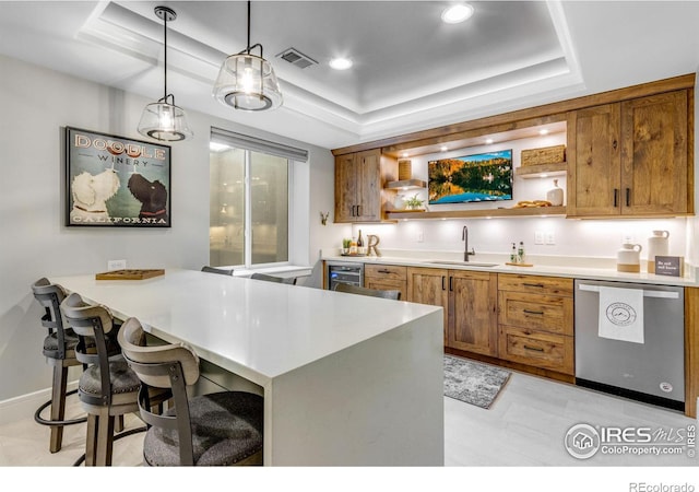 kitchen with dishwasher, a sink, visible vents, and a raised ceiling