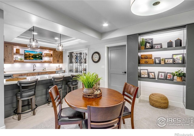 dining area featuring a tray ceiling, wet bar, light carpet, and recessed lighting