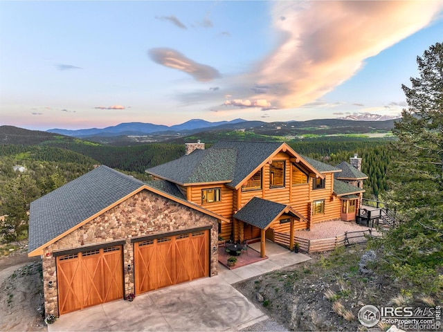 4 Dill Pickle Pl, Black Hawk, CO 80422 - view of front of house featuring a chimney, a mountain view, stone siding, an attached garage, and log siding