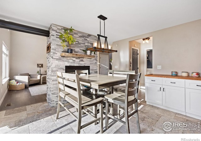 dining area with stone tile floors, baseboards, and a large fireplace