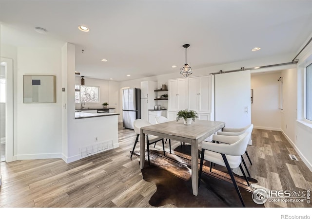 dining area featuring light wood-type flooring, plenty of natural light, baseboards, and visible vents