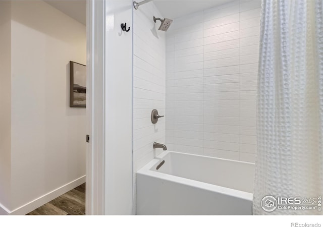 bathroom with baseboards, wood finished floors, and shower / bathtub combination with curtain