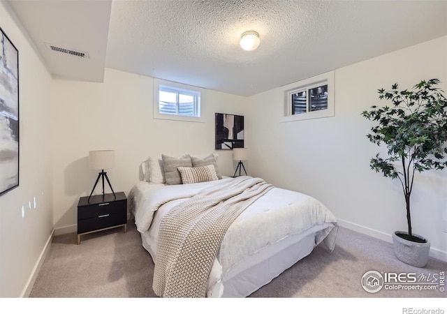 bedroom with carpet flooring, a textured ceiling, and visible vents