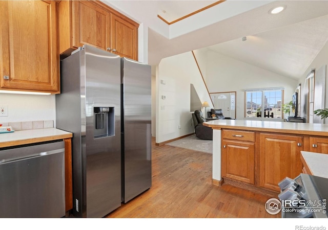 kitchen featuring open floor plan, stainless steel appliances, light countertops, and light wood-type flooring