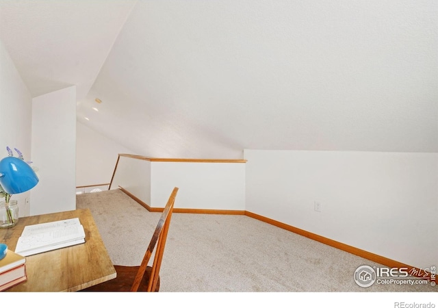 unfurnished office with lofted ceiling, carpet flooring, and baseboards