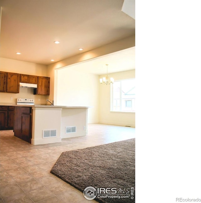8710 8th St, Greeley, CO 80634 - kitchen featuring a chandelier, under cabinet range hood, recessed lighting, light countertops, and range
