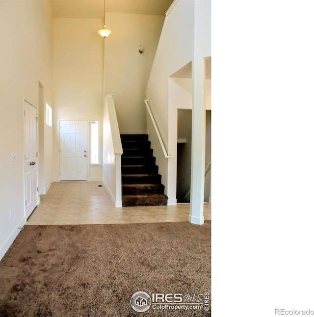 8710 8th St, Greeley, CO 80634 - carpeted entryway with stairs, a towering ceiling, and tile patterned flooring