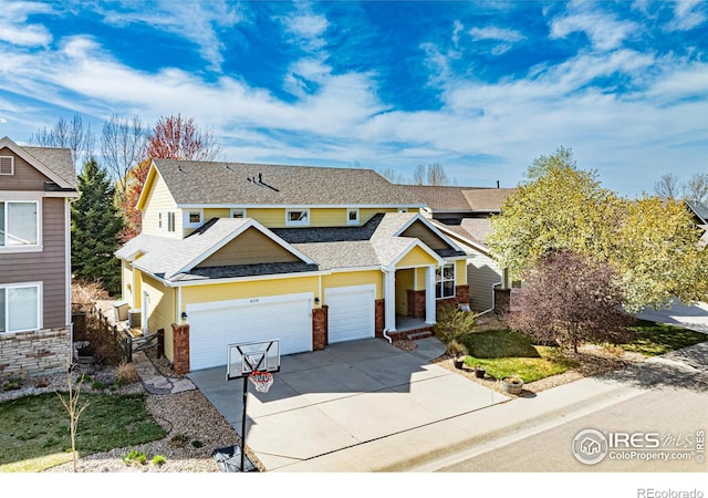 traditional home featuring an attached garage, a shingled roof, and driveway
