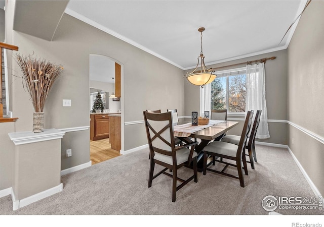 dining space with crown molding, arched walkways, baseboards, and light carpet