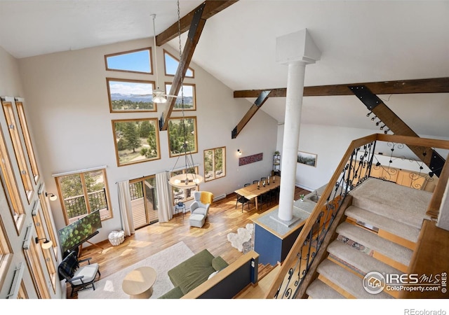 810 Manhead Mountain Dr, Livermore, CO 80536 - living room featuring decorative columns, beamed ceiling, wood finished floors, high vaulted ceiling, and stairway
