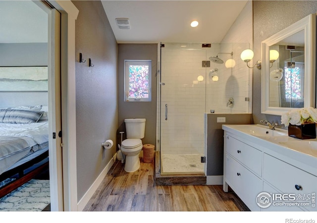 ensuite bathroom featuring a shower stall, wood finished floors, toilet, ensuite bath, and baseboards