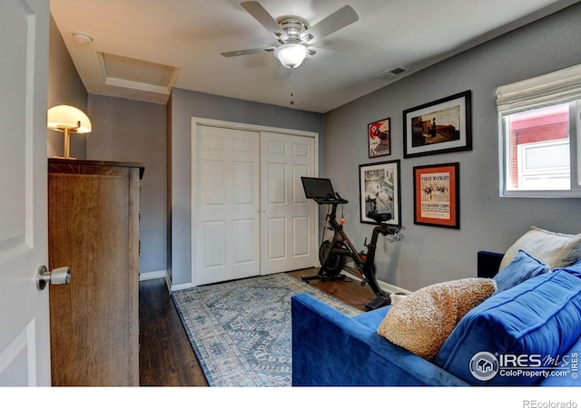 exercise room with attic access, visible vents, baseboards, wood finished floors, and ceiling fan