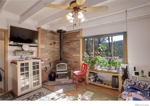 147 Cedar Dr, Lyons, CO 80540 - living area featuring a wood stove, ceiling fan, wood finished floors, and beamed ceiling