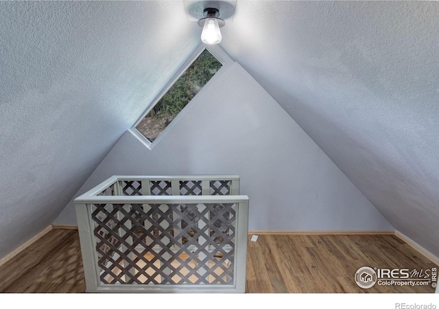 147 Cedar Dr, Lyons, CO 80540 - additional living space with lofted ceiling, baseboards, wood finished floors, and a textured ceiling