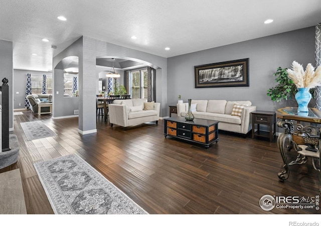 338 Mt Wilson St, Brighton, CO 80601 - living area with arched walkways, dark wood-style floors, recessed lighting, decorative columns, and a textured ceiling