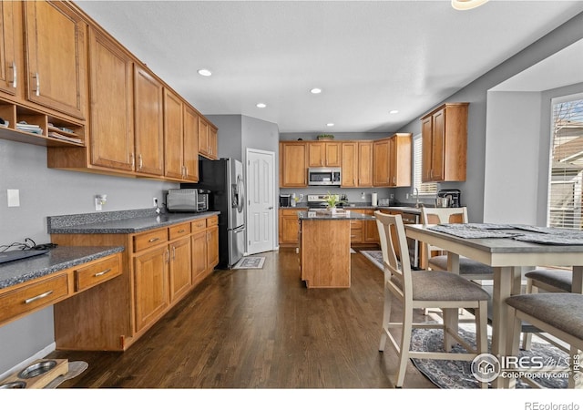 338 Mt Wilson St, Brighton, CO 80601 - kitchen with stainless steel appliances, dark wood-style flooring, a center island, dark countertops, and brown cabinets