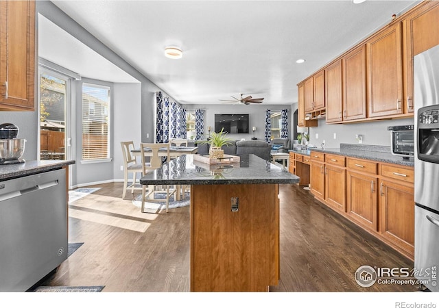 338 Mt Wilson St, Brighton, CO 80601 - kitchen featuring appliances with stainless steel finishes, a kitchen island, a ceiling fan, dark wood-style flooring, and brown cabinetry
