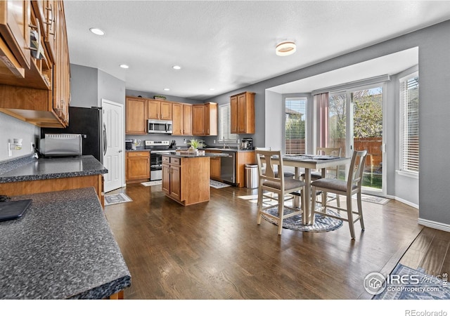338 Mt Wilson St, Brighton, CO 80601 - kitchen featuring appliances with stainless steel finishes, dark wood finished floors, a kitchen island, recessed lighting, and brown cabinetry
