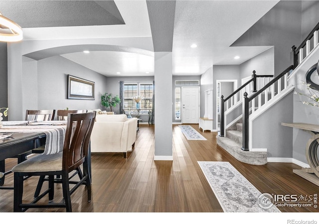 338 Mt Wilson St, Brighton, CO 80601 - dining area featuring arched walkways, dark wood-style floors, recessed lighting, and stairway